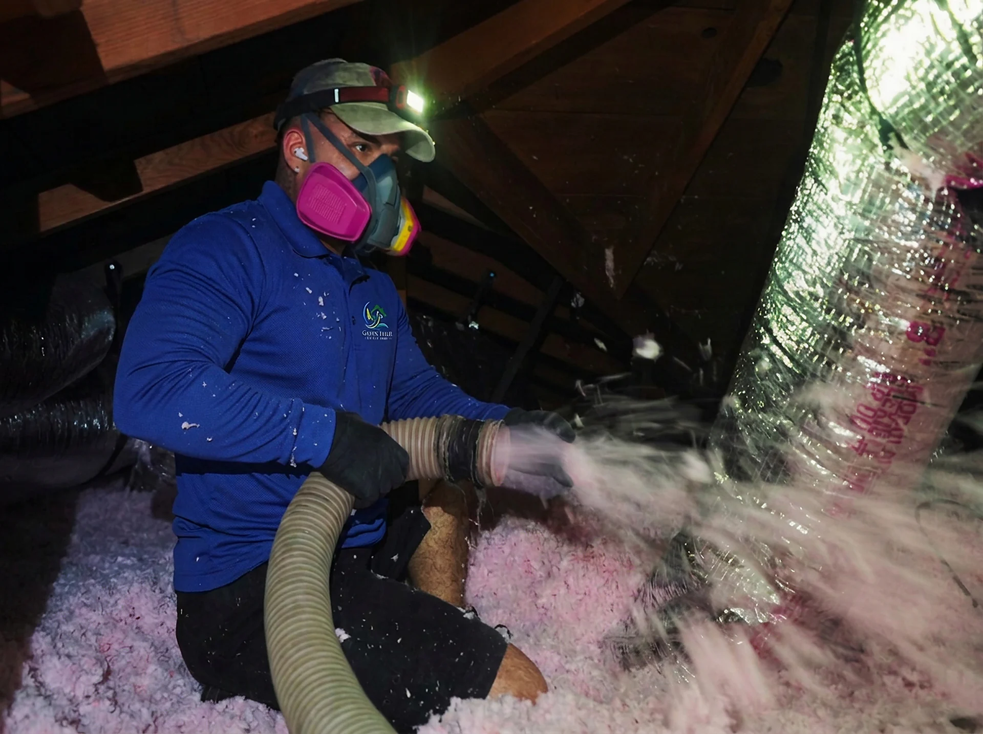 Green Faith Solutions installer applying blown-in insulation in an attic