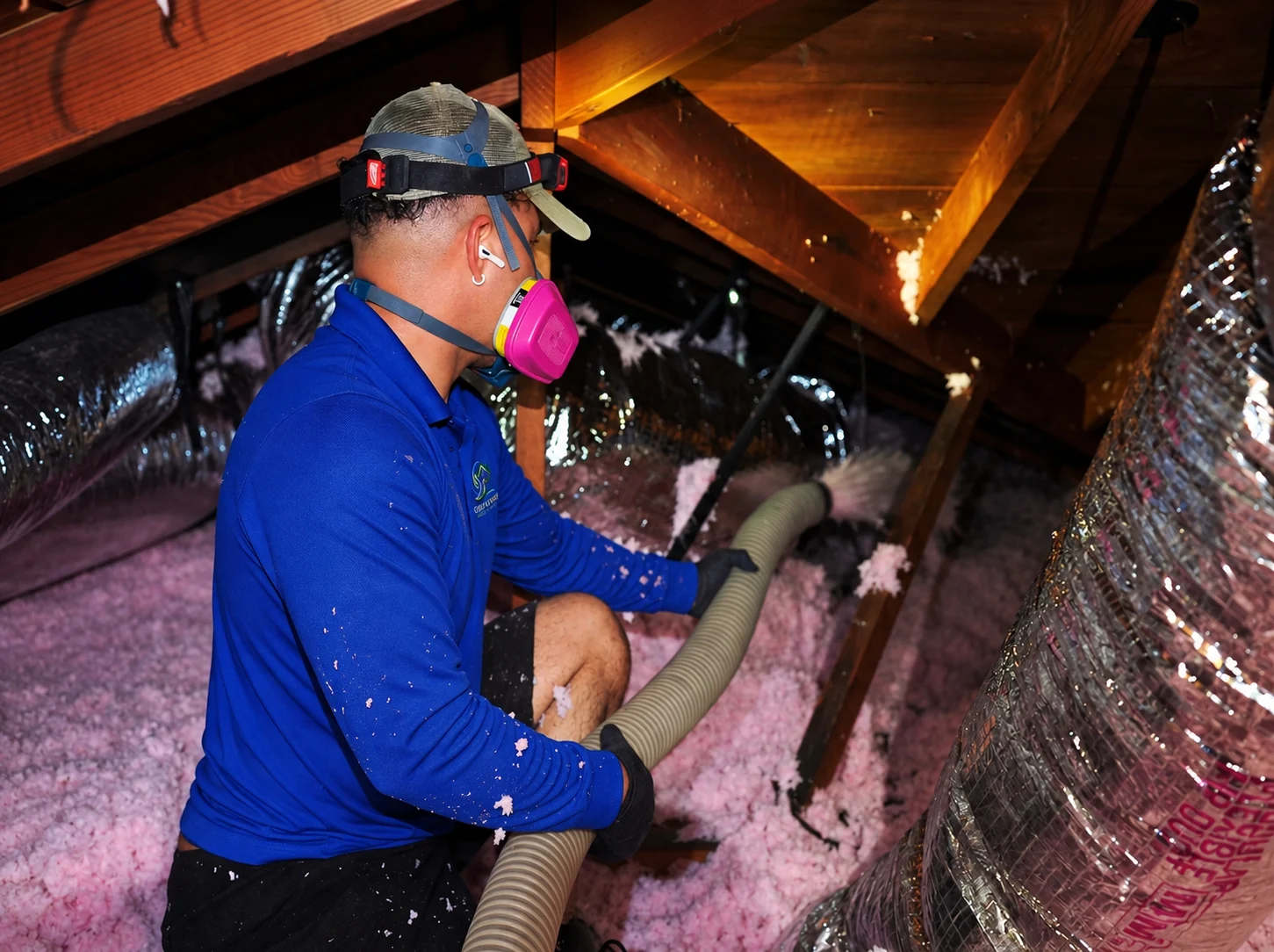 Green Faith Solutions installer applying blown-in insulation in an attic